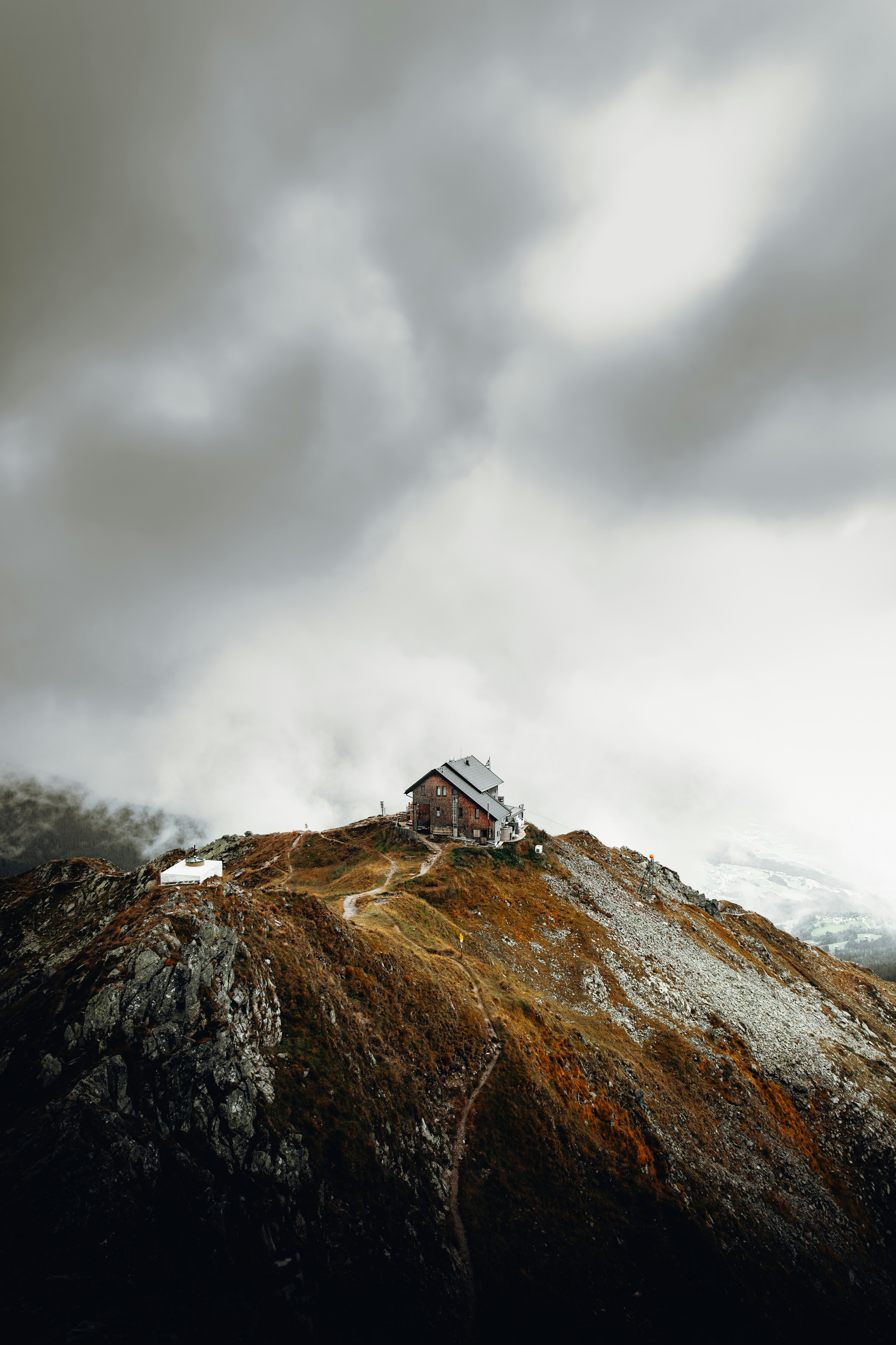 white and brown house on top of brown mountain under white clouds